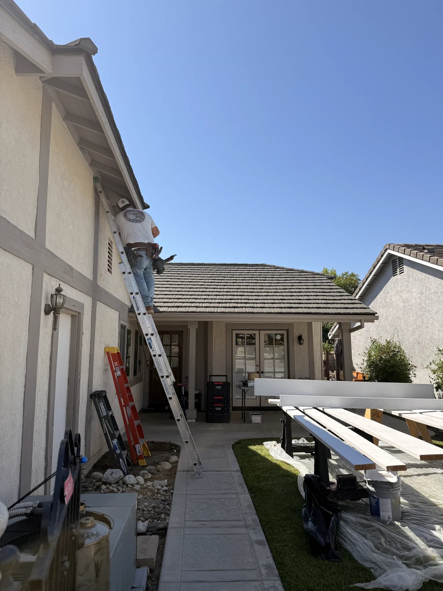 A custom home under a clear Santa Clarita sky, with a CMOC crew member at work.
