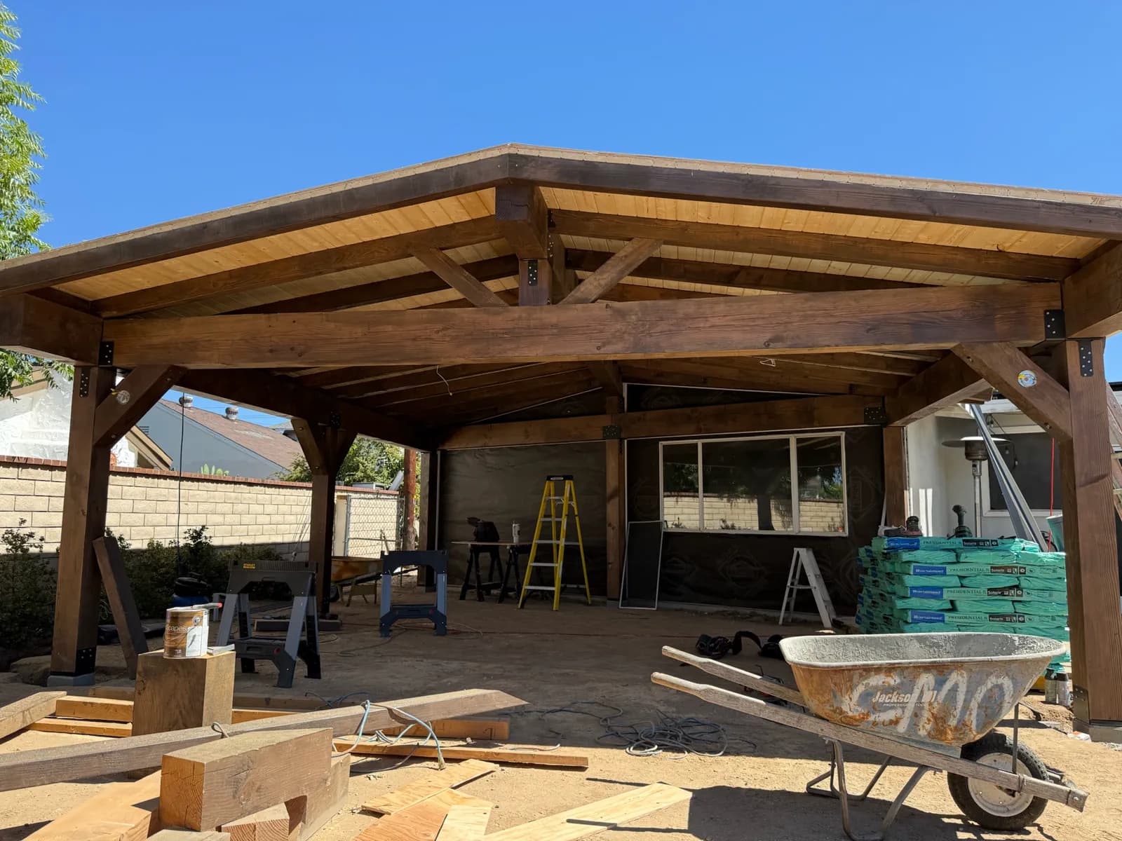 A backyard patio cover nearing completion with the wood ceiling installed.